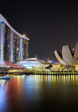 Stunning night view of Marina Bay Sands and Helix Bridge illuminated over water in Singapore.
