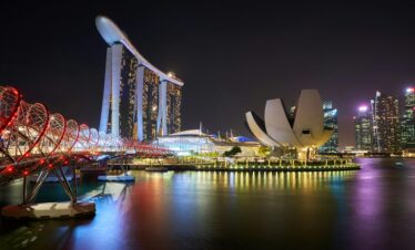 Stunning night view of Marina Bay Sands and Helix Bridge illuminated over water in Singapore.