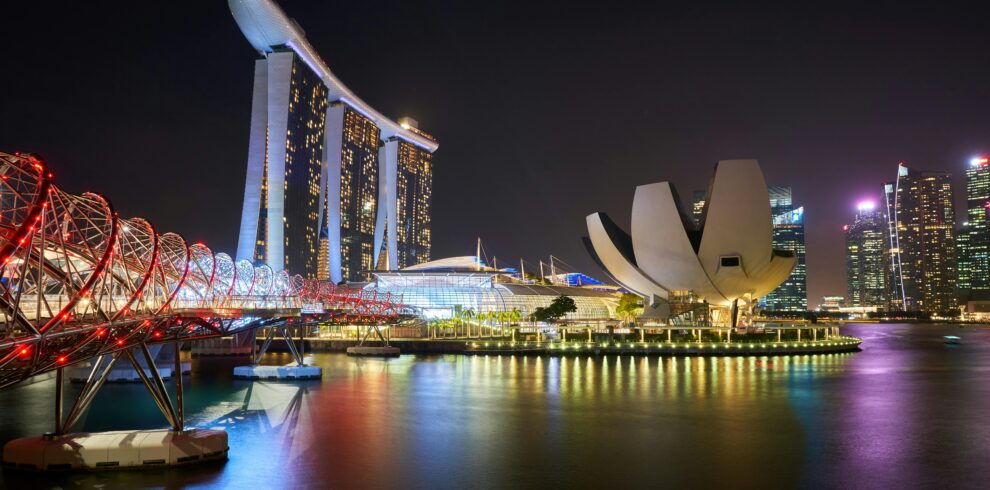 Stunning night view of Marina Bay Sands and Helix Bridge illuminated over water in Singapore.