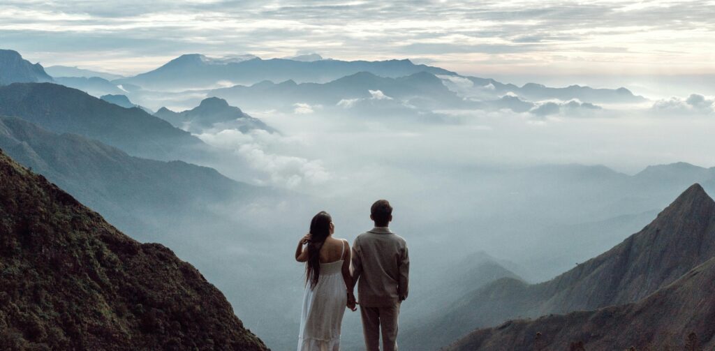 A couple stands hand in hand marveling at the breathtaking Munnar mountain landscape.