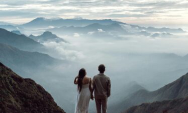 A couple stands hand in hand marveling at the breathtaking Munnar mountain landscape.