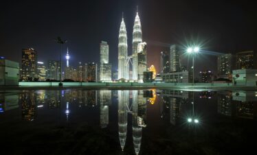 Beautiful view of Kuala Lumpur's skyline featuring the iconic Petronas Towers at night with city lights and reflections.