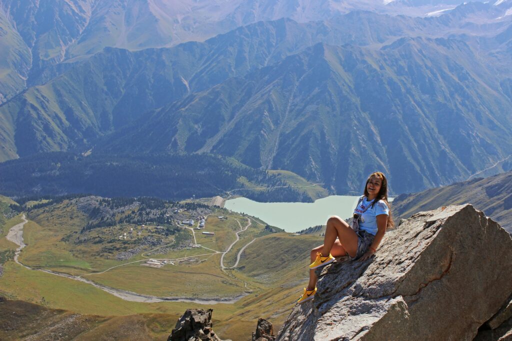 A woman enjoys a breathtaking view from a mountaintop in Almaty, Kazakhstan.