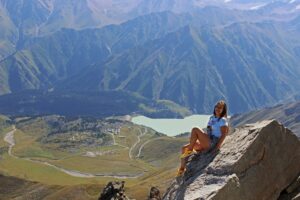 A woman enjoys a breathtaking view from a mountaintop in Almaty, Kazakhstan.