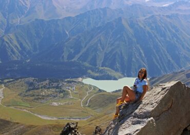 A woman enjoys a breathtaking view from a mountaintop in Almaty, Kazakhstan.