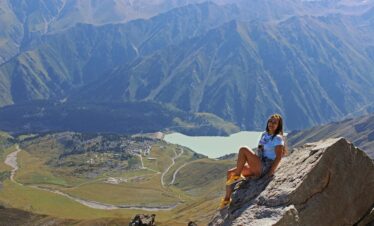 A woman enjoys a breathtaking view from a mountaintop in Almaty, Kazakhstan.