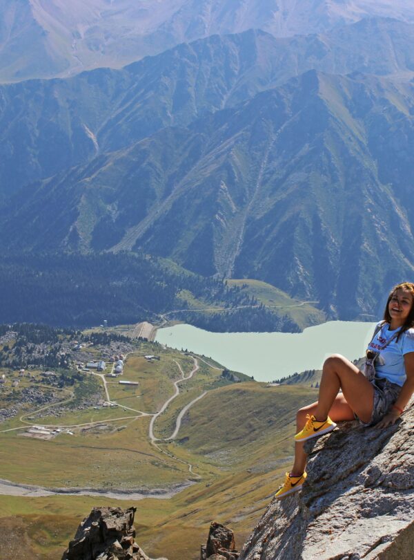A woman enjoys a breathtaking view from a mountaintop in Almaty, Kazakhstan.