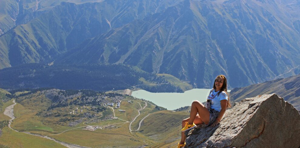 A woman enjoys a breathtaking view from a mountaintop in Almaty, Kazakhstan.