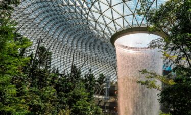 The iconic indoor waterfall at Jewel Changi Airport surrounded by lush gardens.