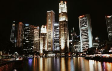 Illuminated skyline reflecting in water, showcasing Singapore's modern architecture.