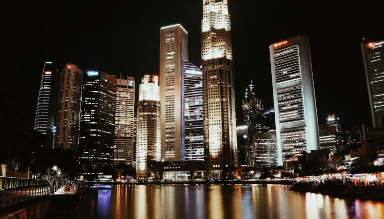 Illuminated skyline reflecting in water, showcasing Singapore's modern architecture.