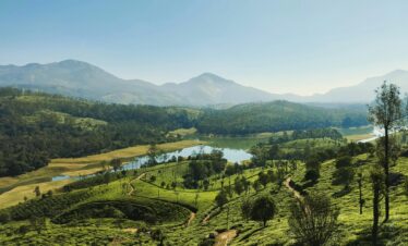 A breathtaking aerial view of Munnar, India, showcasing lush tea plantations and a serene river.