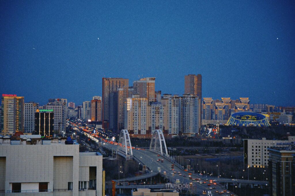 Breathtaking view of Astana's skyline with an illuminated bridge during the night.