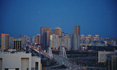 Breathtaking view of Astana's skyline with an illuminated bridge during the night.