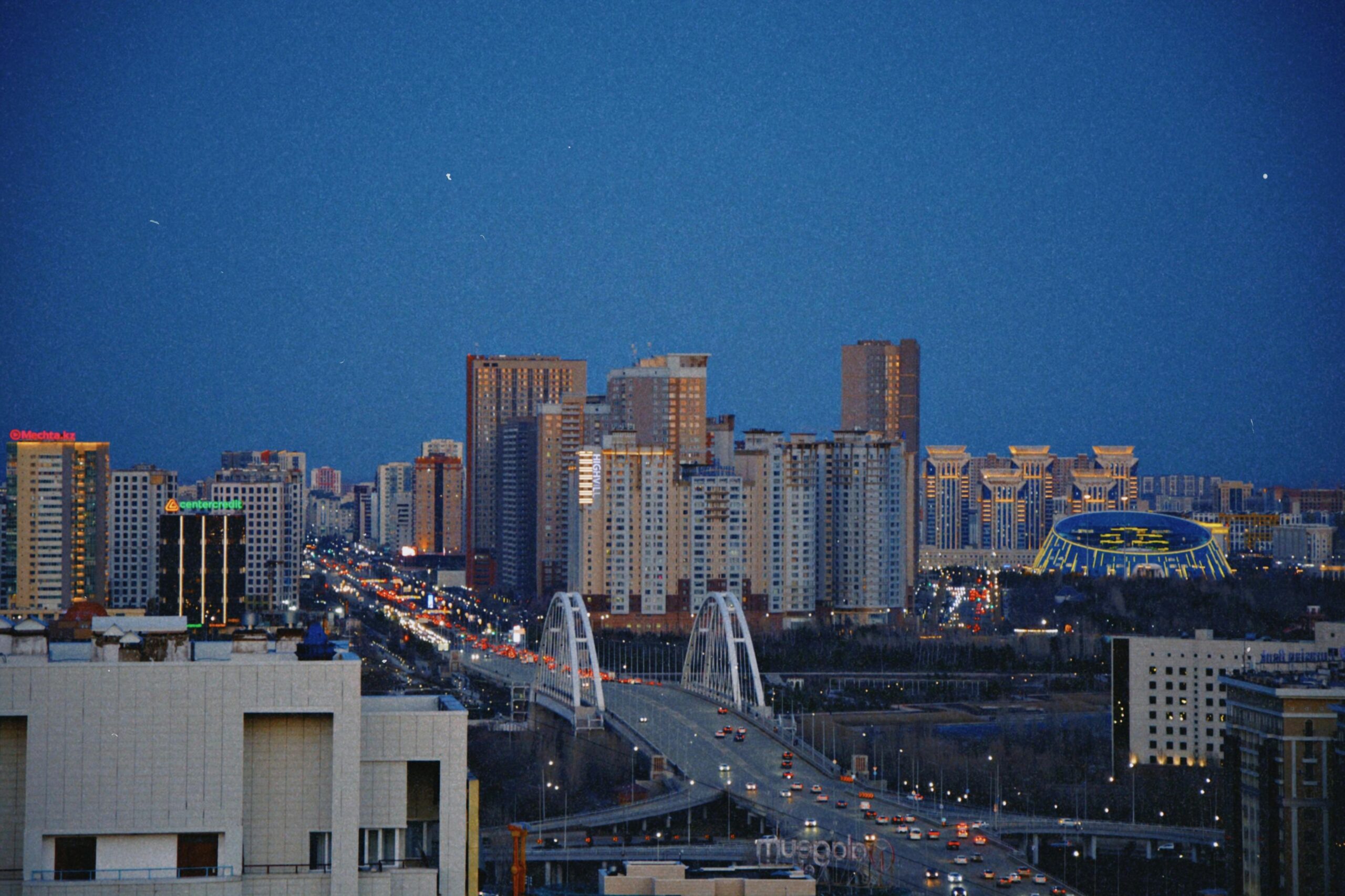 Breathtaking view of Astana's skyline with an illuminated bridge during the night.