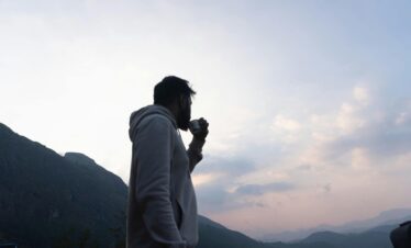 A man drinks coffee while enjoying a stunning view of the mountains in Munnar, Kerala.