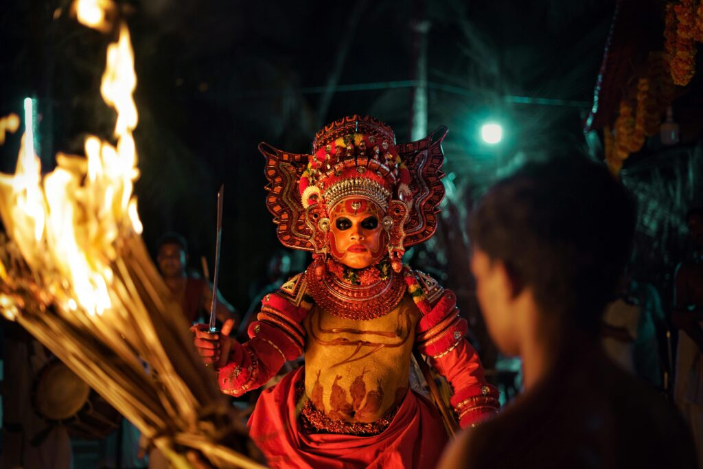 Captivating image of a traditional Theyyam performer with fire in a night festival setting.