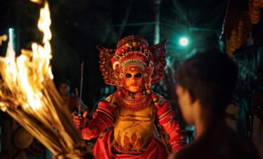 Captivating image of a traditional Theyyam performer with fire in a night festival setting.