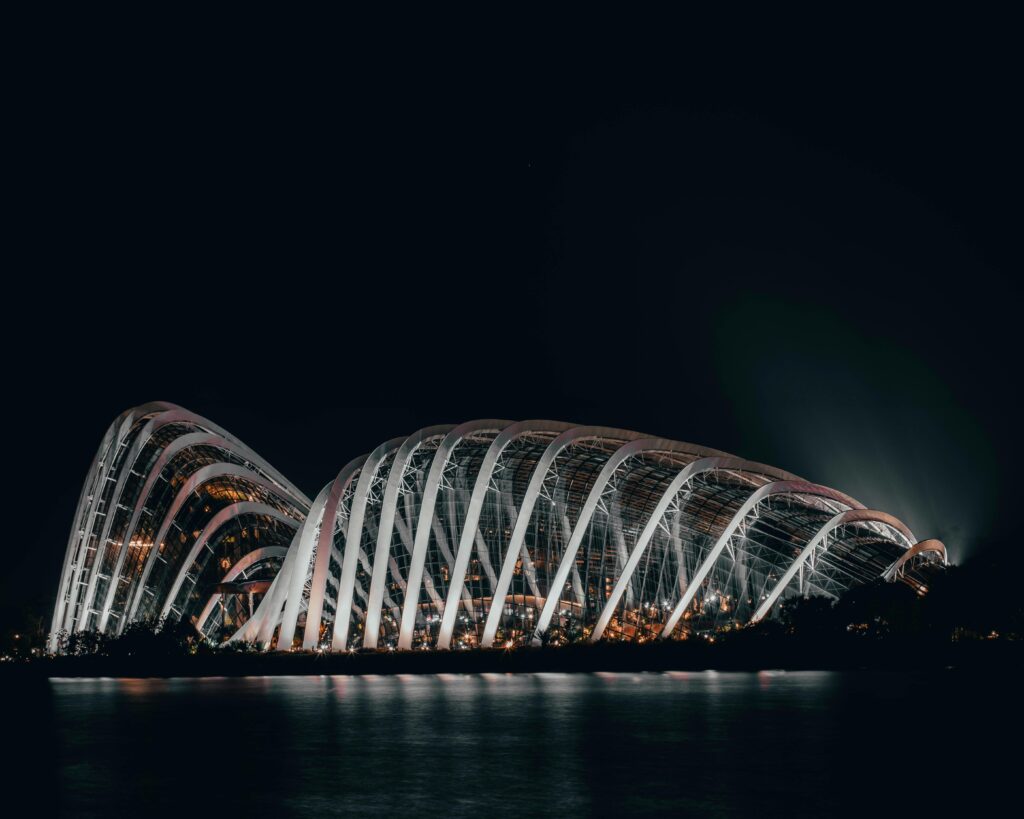 Dramatic night shot of the illuminated Flower Dome in Singapore, showcasing its modern architecture.