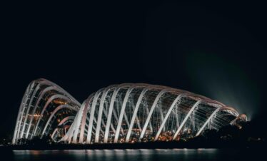 Dramatic night shot of the illuminated Flower Dome in Singapore, showcasing its modern architecture.