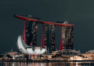 Dramatic night view of Marina Bay Sands, Singapore, with glowing cityscape and reflection.