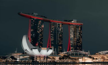 Dramatic night view of Marina Bay Sands, Singapore, with glowing cityscape and reflection.