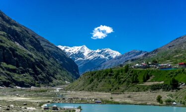 Captivating view of Jispa valley with snow-capped peaks and a serene lake under a clear blue sky.