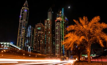 Stunning night view of Dubai's illuminated skyscrapers and palm trees with light trails from passing cars.