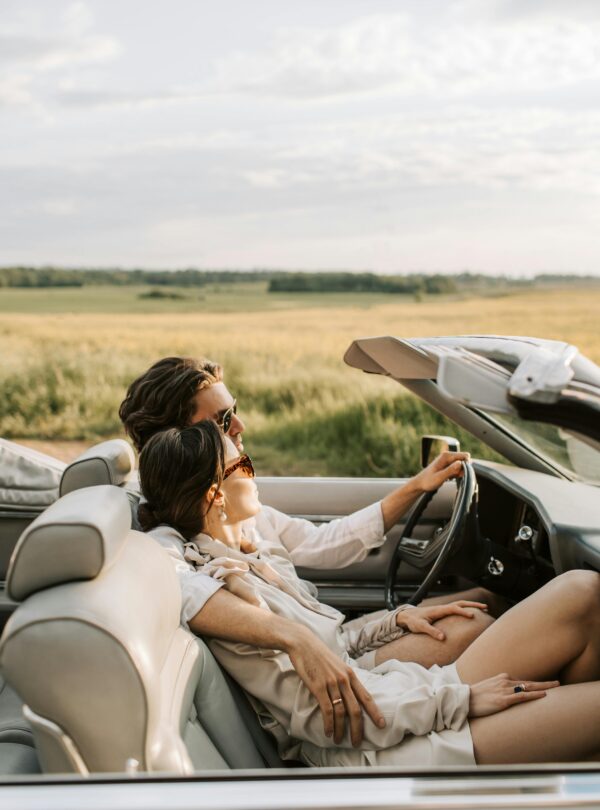 A couple enjoys a romantic drive through scenic fields in a stylish convertible.